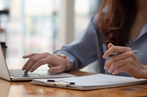 Cropped close up photo of writing down essential details of online conference having just been held on laptop.